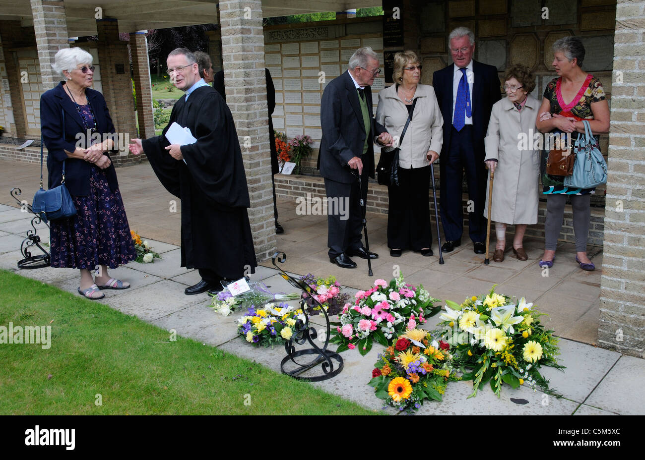Trauernden und Priester bei einer Beerdigung sprechen und bewundern Sie Blumen und Kränze an einem Krematorium Stockfoto