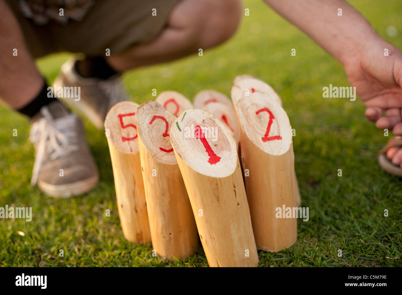 Menschen spielen eine hausgemachte Version des finnischen outdoor-Spiel "Molkky" beinhaltet nummerierten Holzstifte mit einem Stock schlagen Stockfoto