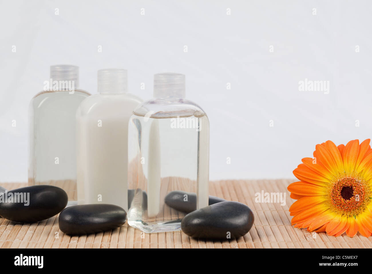 Sonnenblume mit schwarzen Steinen und Massage-Öl-Flaschen Stockfoto