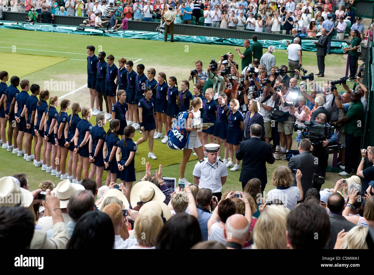 Spieler gehen Sie durch die Linie der Ball jungen und Mädchen nach bei den 2011 Wimbledon Tennis Championships Finale Damen Stockfoto