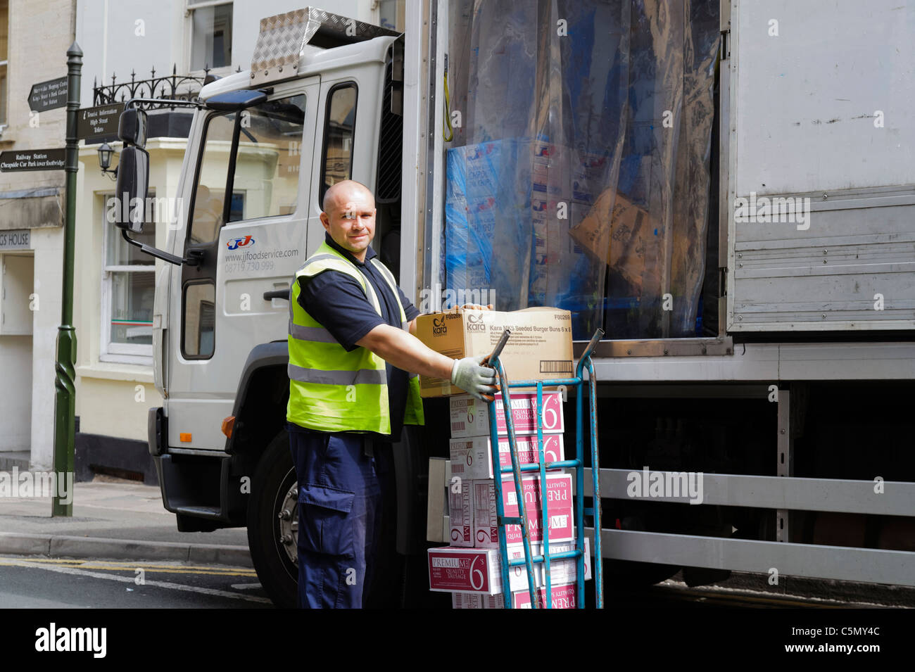 Mann entladen Essen von der Seite eines gekühlten LKWs, Stroud, UK. Gekühlten LKW Fahrer mit einem Sack LKW entladen wird. Stockfoto