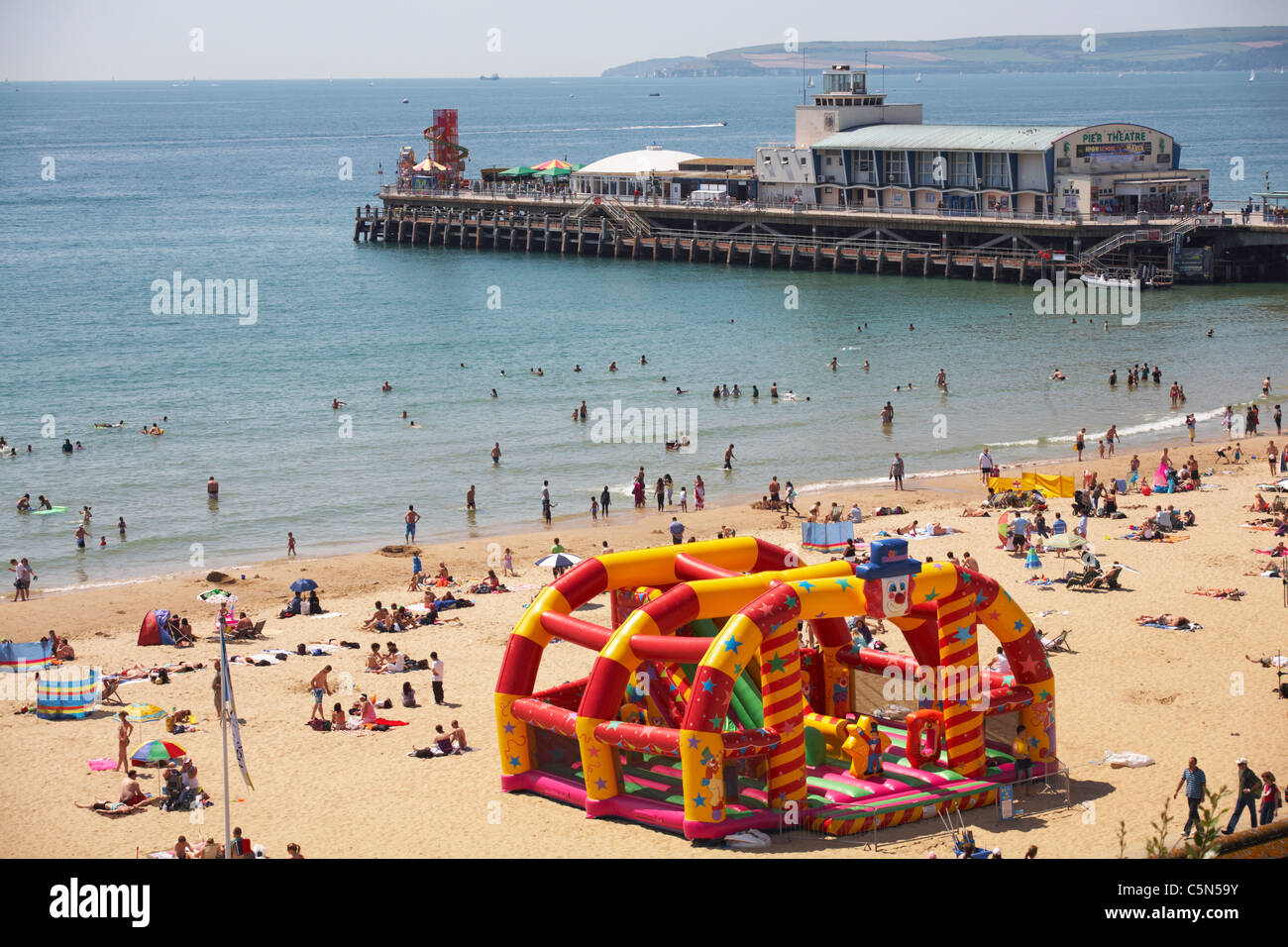 Menschen, die genießen Bournemouth direkt am Meer mit Strand und Pier im Sommer mit Purbecks und Old Harry Rocks in der Ferne Stockfoto