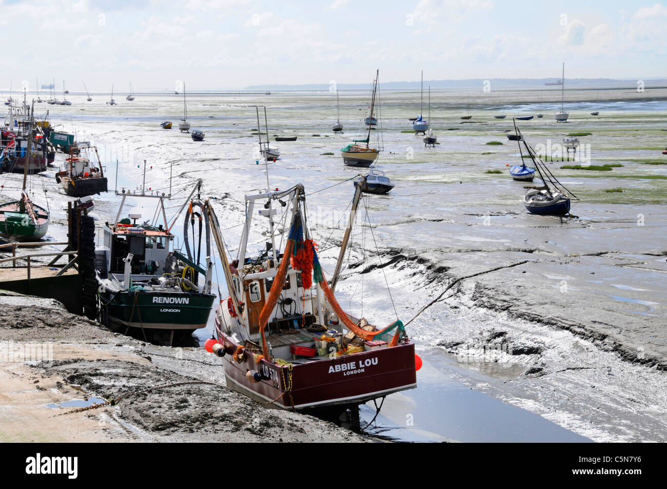 Fischboote mit Muscheln und Muscheln, die in der Themse-Mündung auf Schlammflächen im Ebbe des Old Leigh Essex Coast Kent Coastline und Boote im fernen England, Großbritannien, liegen Stockfoto