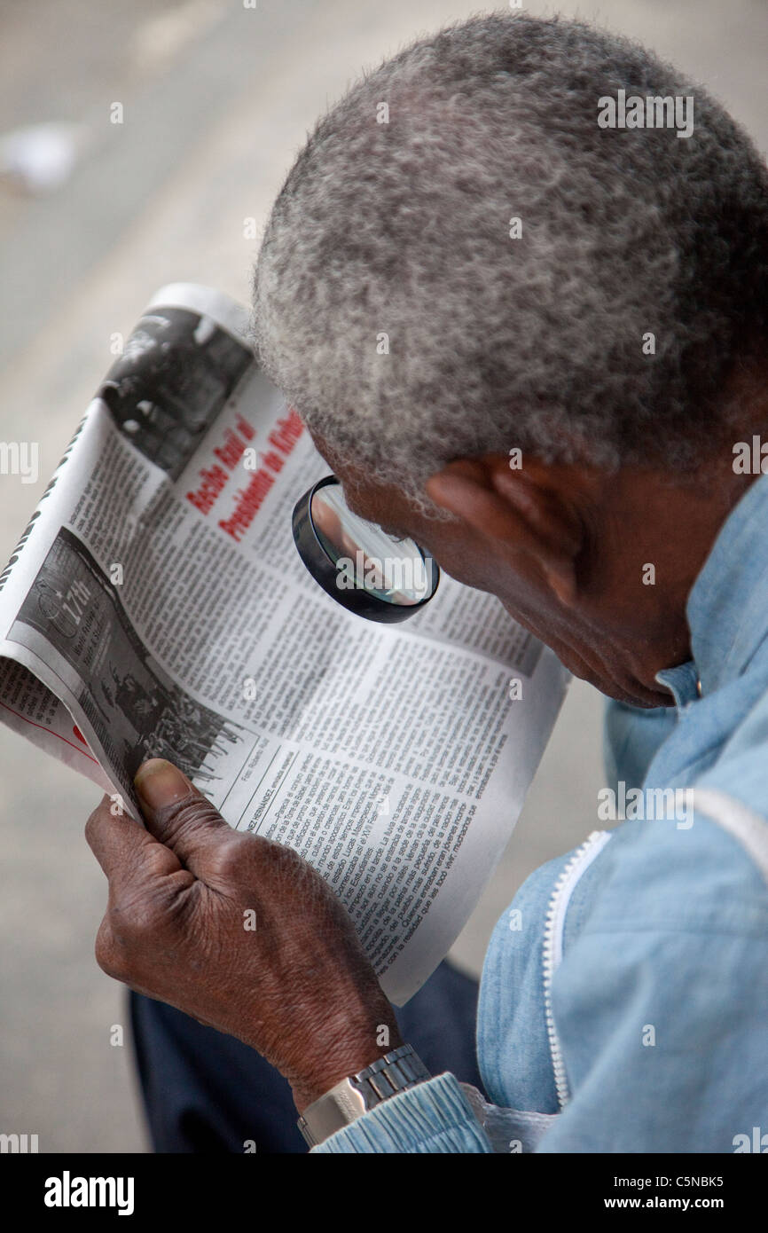 Kuba, Havanna. Mann mit Lupe, Granma, die offizielle Party Zeitung zu lesen. Stockfoto