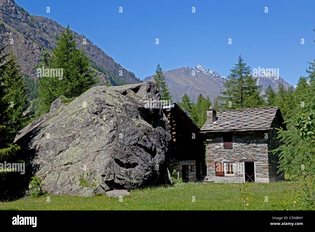 Der Kontrast zwischen ein kleines Haus mit einem großen Findling (Italien). Amusant Contraste Entre Une Maison et un Énorme Bloc Findling. Stockfoto