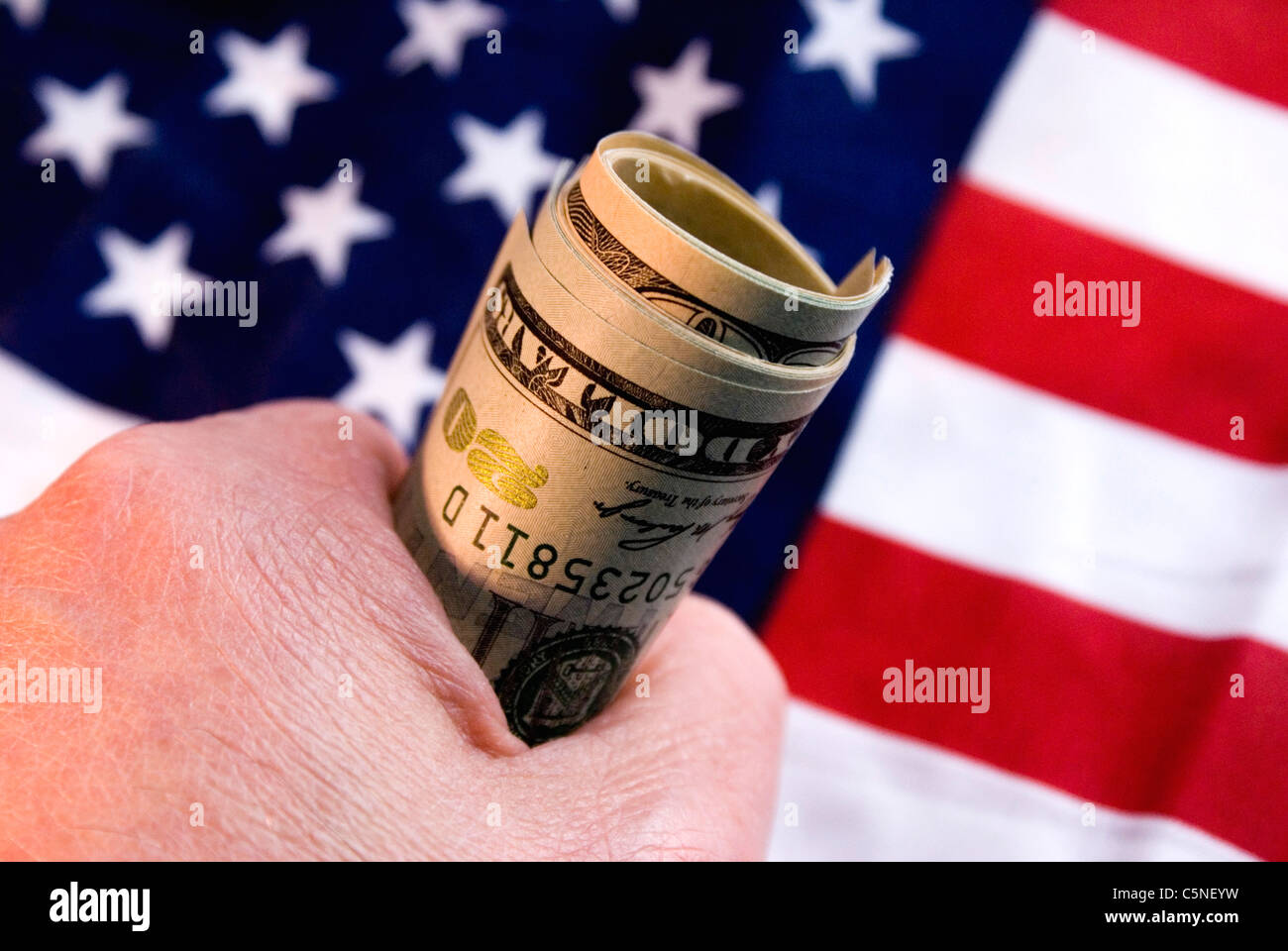 Eine Handvoll US-Dollar mit Sternen und Streifen im Hintergrund Stockfoto