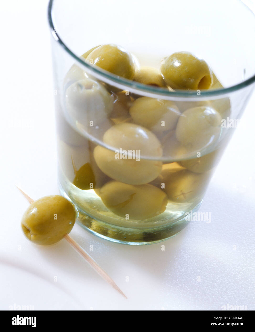 Kleines Glas mit grünen Oliven und Zahnstocher Stockfoto