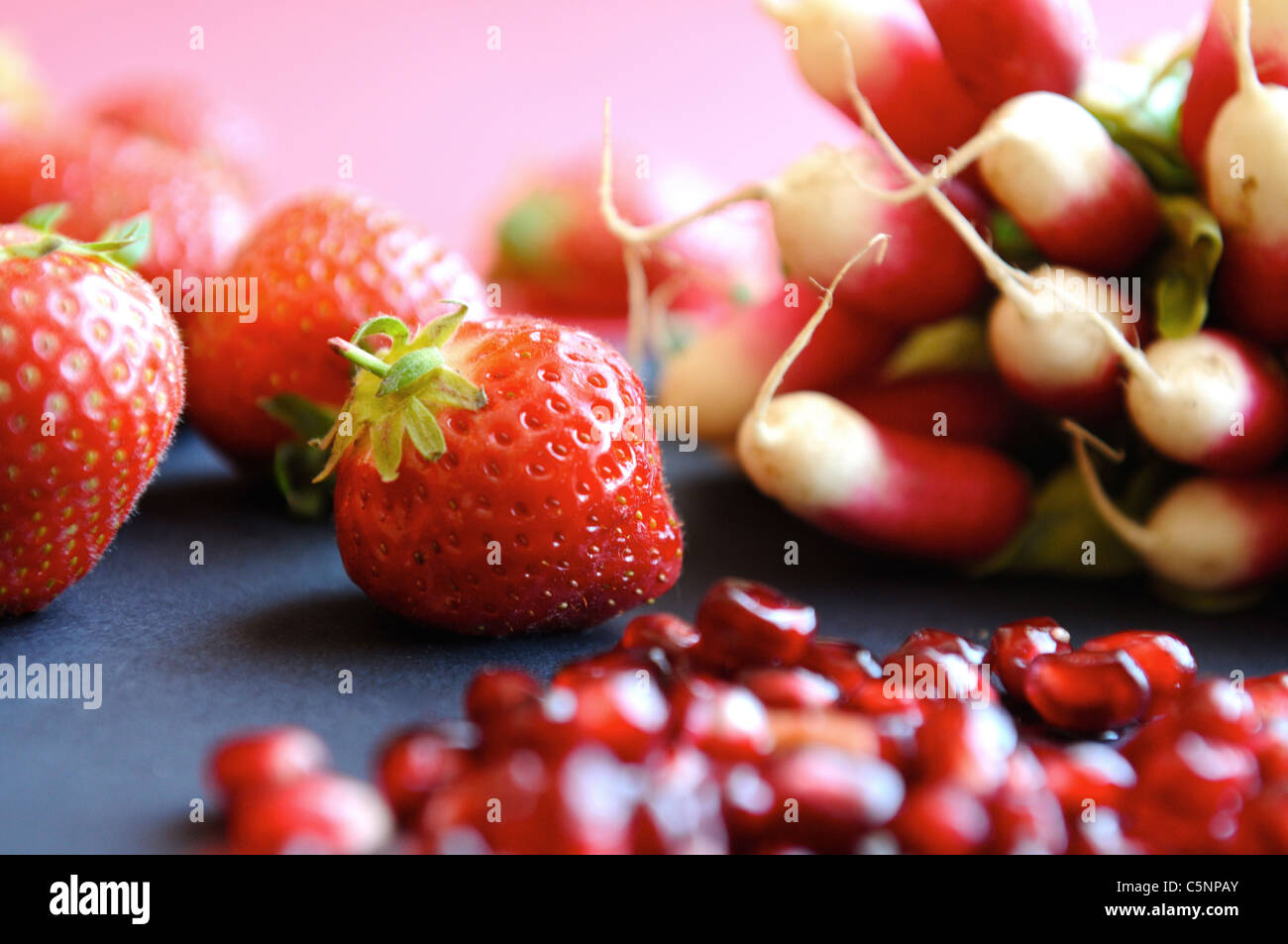 Rote Früchte und Gemüse: Erdbeeren, Radieschen und Granatapfel Stockfoto