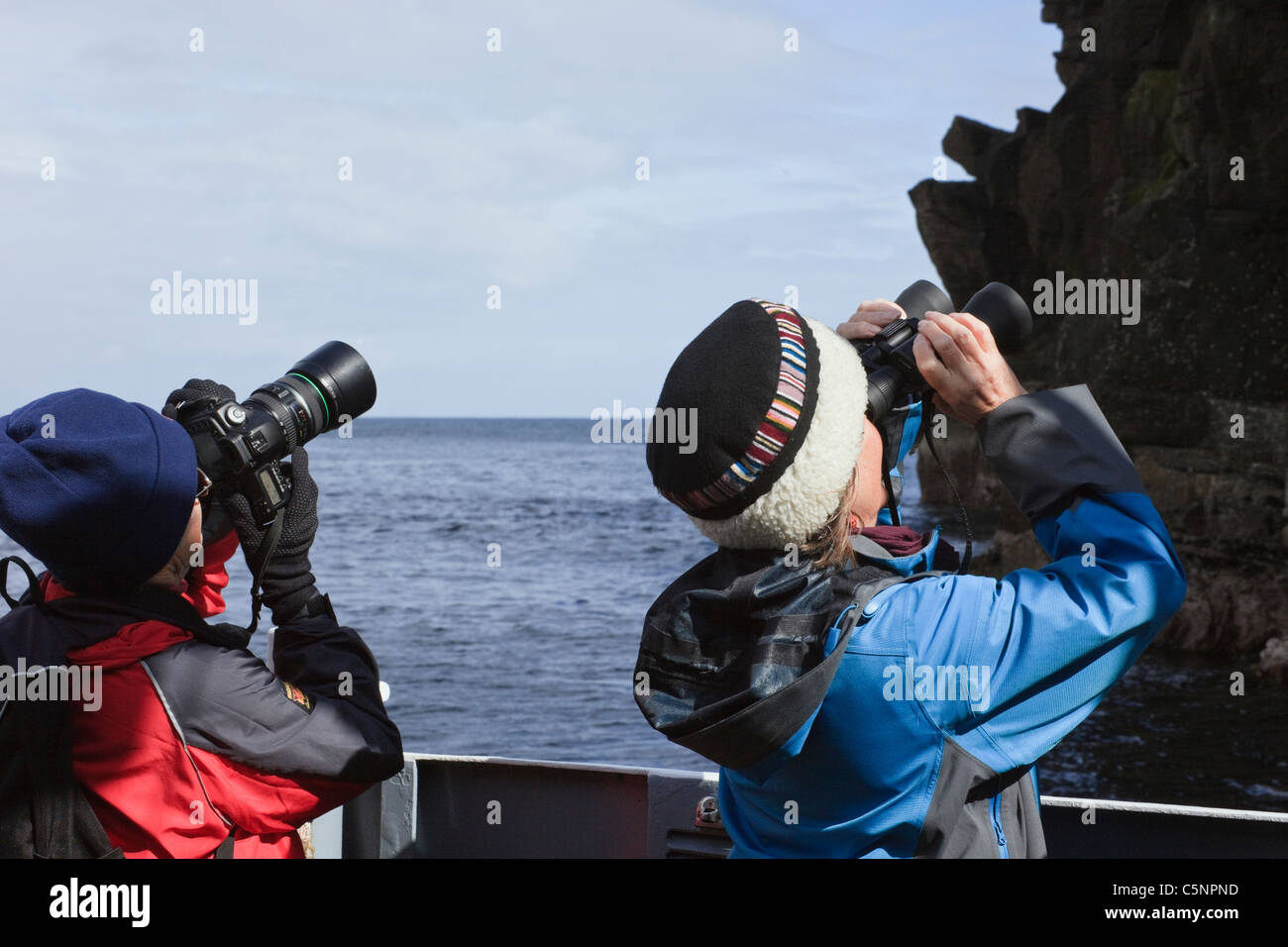 Zwei Frauen Vogelbeobachtung auf einen Bootsausflug zu den Basstölpel nisten auf den Seacliffs im Sommer. Noss, Shetland Islands, Schottland, Großbritannien. Stockfoto