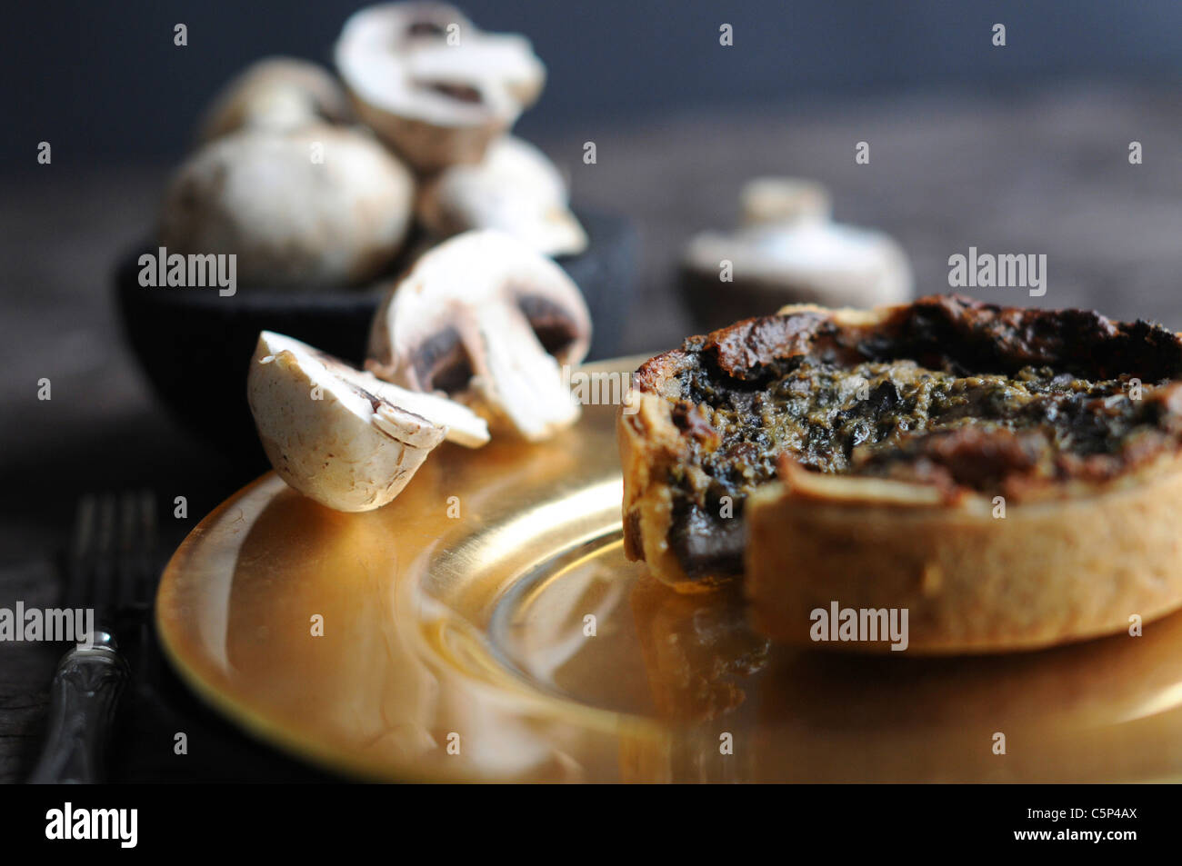 Kleine Spinat-Champignon-Quiche auf einem goldenen Teller Stockfoto