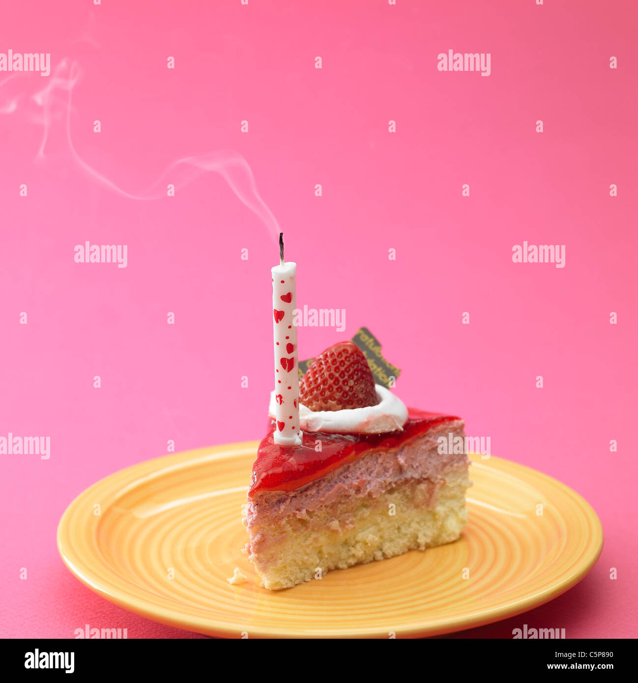 Stück Kuchen auf einem Teller mit Kerze auf Stockfoto
