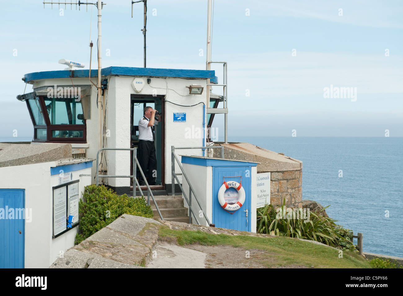 Ein Rettungsschwimmer verwendet Fernglas, Blick auf das Meer von einem Lookout-Station in St. Ives, Cornwall. Stockfoto