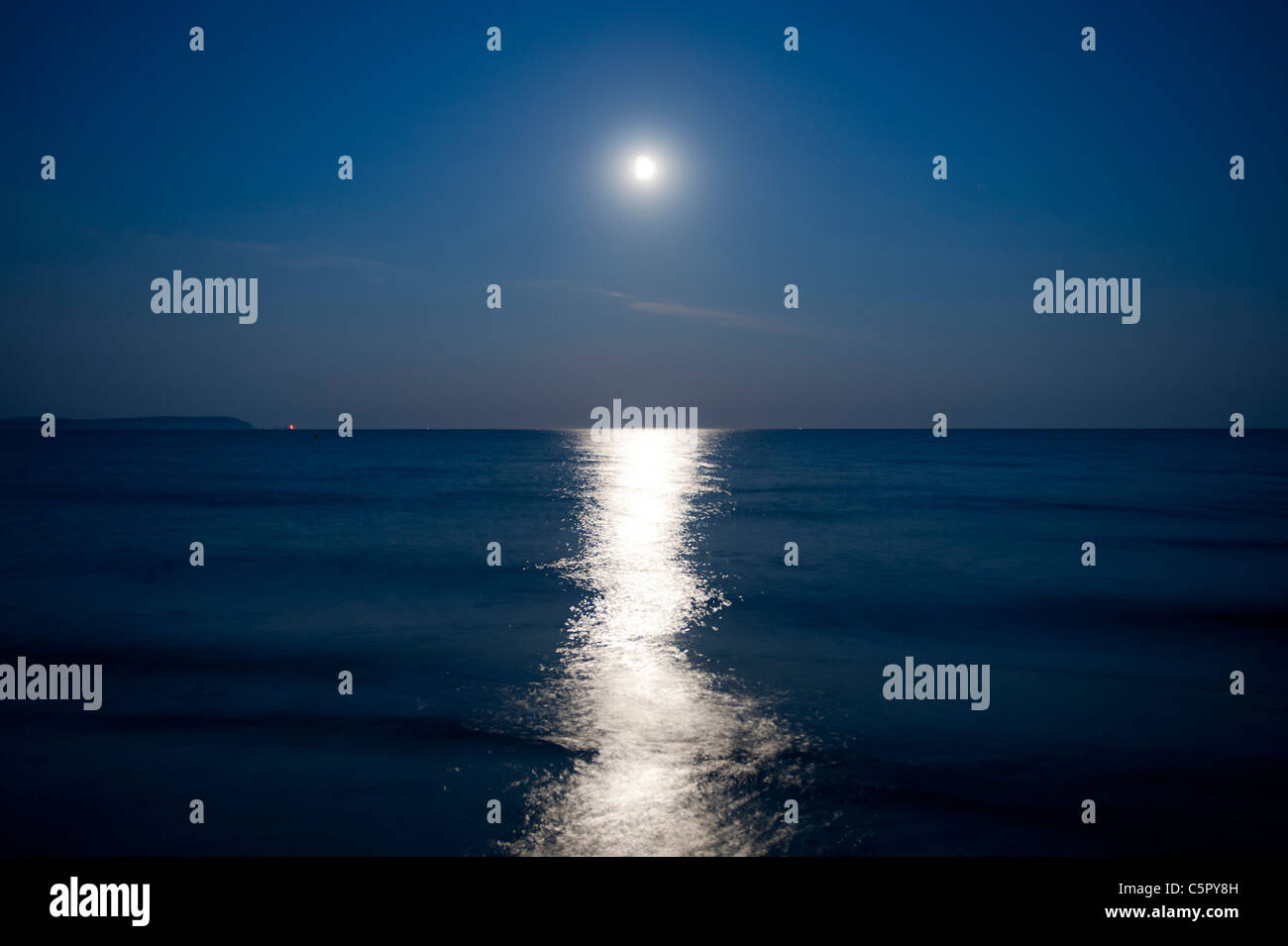 Mondlicht sendet eine Reflexion über eine ruhige Nacht-Meer von der Küste zuvorkommend, Dorset. Stockfoto