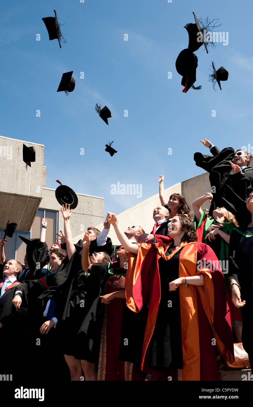Eine Gruppe von Aberystwyth Universität Absolventen am Abschlusstag, werfen ihre Mützen in die Luft, UK Stockfoto