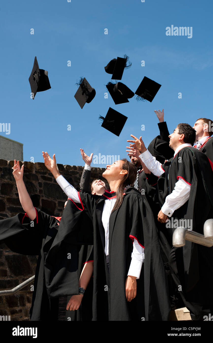 Eine Gruppe von Aberystwyth Universität Absolventen am Abschlusstag, werfen ihre Mützen in die Luft, UK Stockfoto