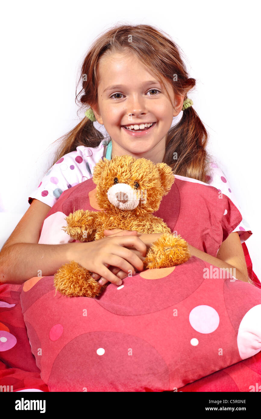 acht Jahre altes Mädchen im Bett mit einem Teddy-Bären Stockfoto