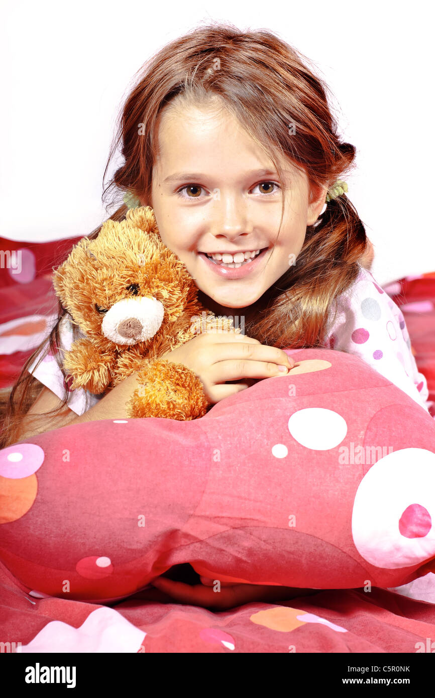 acht Jahre altes Mädchen im Bett mit einem Teddy-Bären Stockfoto