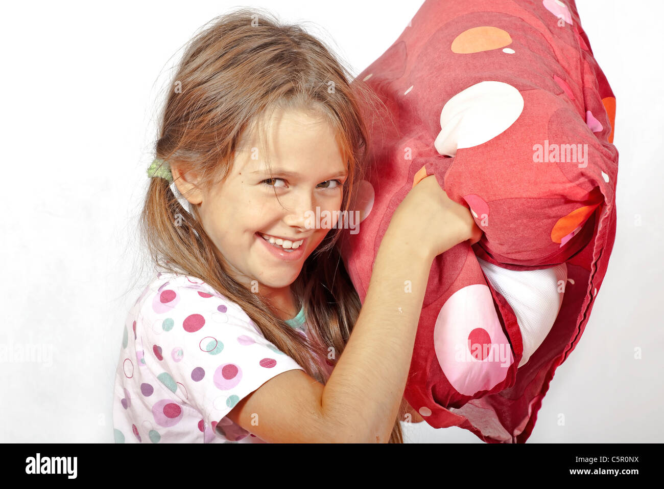 acht Jahre altes Mädchen im Bett tun eine Kissenschlacht Stockfoto