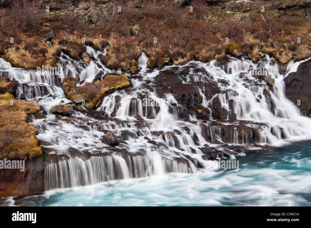 Wasserfall aus vulkanischer Lava fließt ein Fluss, Hraunfossar, Berggipfeln, Island Stockfoto