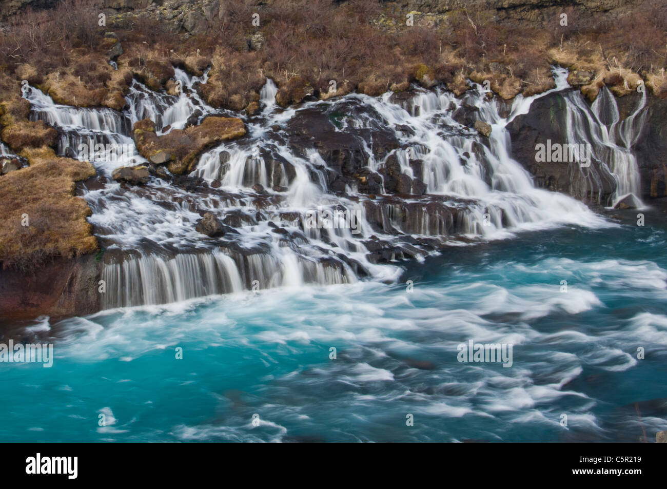 Wasserfall aus vulkanischer Lava fließt ein Fluss, Hraunfossar, Berggipfeln, Island Stockfoto