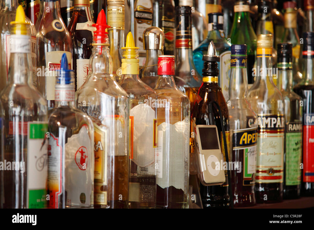 einen Ipod zwischen Flaschen Alkohol auf einem Regal in einer bar Stockfoto