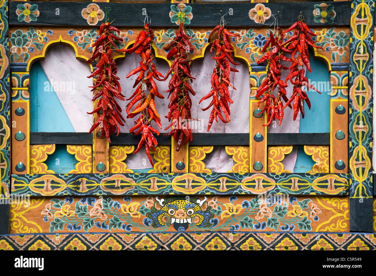 Rote Chili/Paprika trocknen vor dem bunten Fenster in Paro, Bhutan Stockfoto