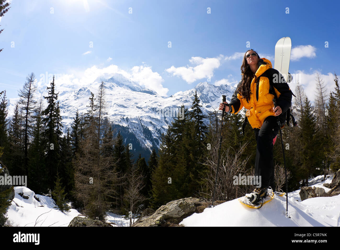 Ein Mädchen in den alpinen Bergen mit Schneeschuhen und Snowbard für die Fahrt nach unten wandern. Stockfoto