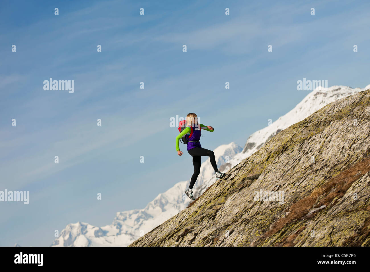Eine Frau, die im Hochgebirge Joggen läuft auf einem steilen Peak. Stockfoto