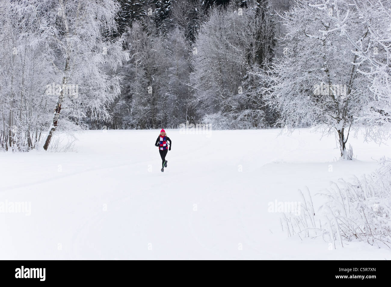 Ein Jogger läuft durch eine tief verschneite Landschaft. Stockfoto