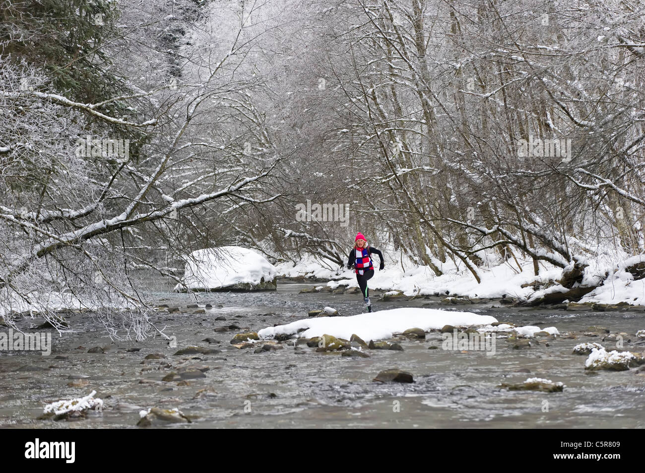 Ein Jogger einen verschneiten alpinen Fluss überquert Stockfoto