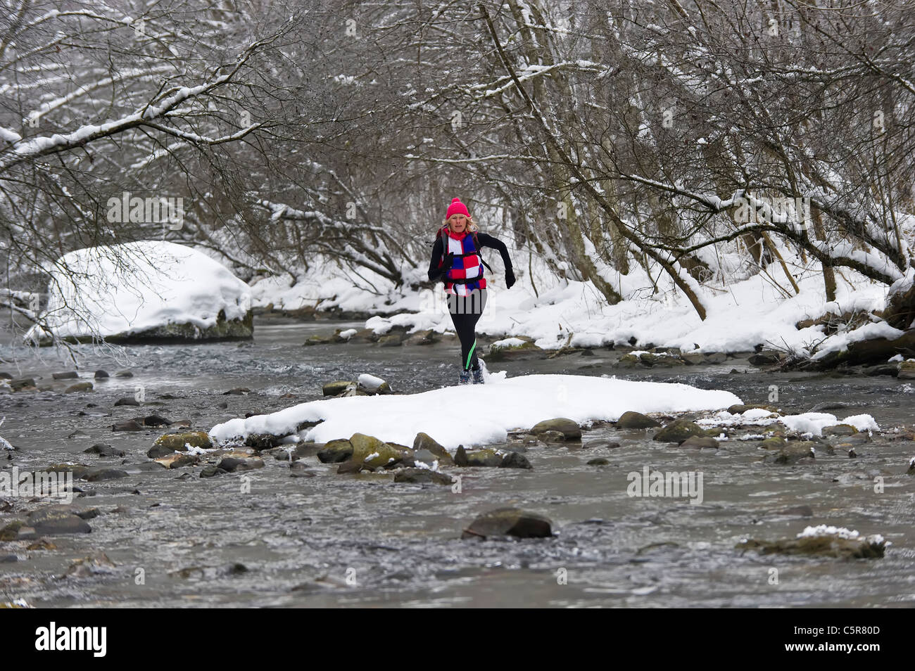 Ein Jogger, einen kalten alpinen Fluss überqueren. Stockfoto