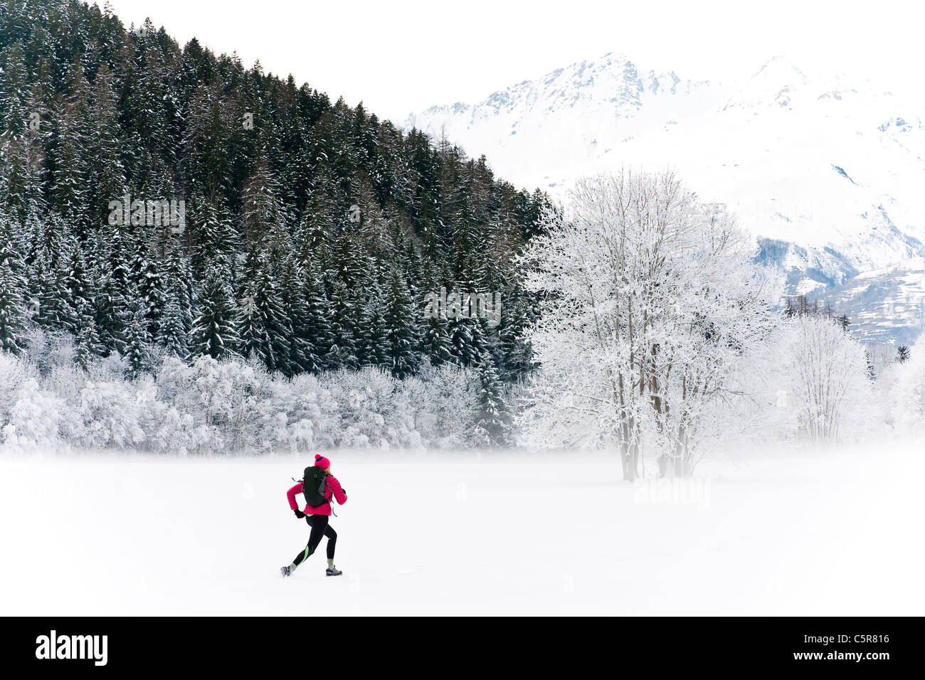 Ein Jogger läuft durch eine winterliche Landschaft. Stockfoto