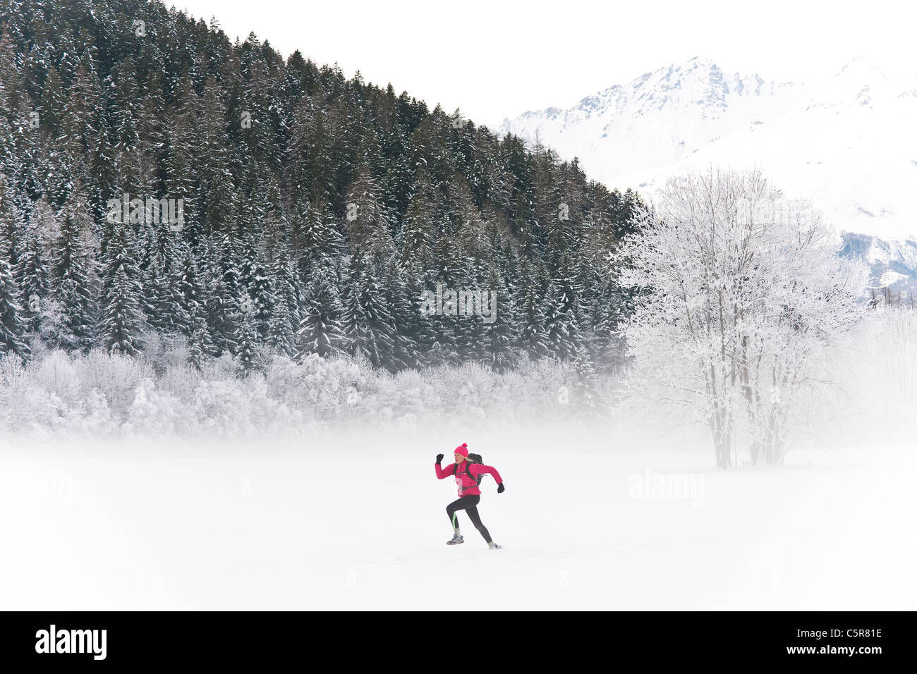 Ein Jogger läuft durch eine verschneite Berglandschaft. Stockfoto