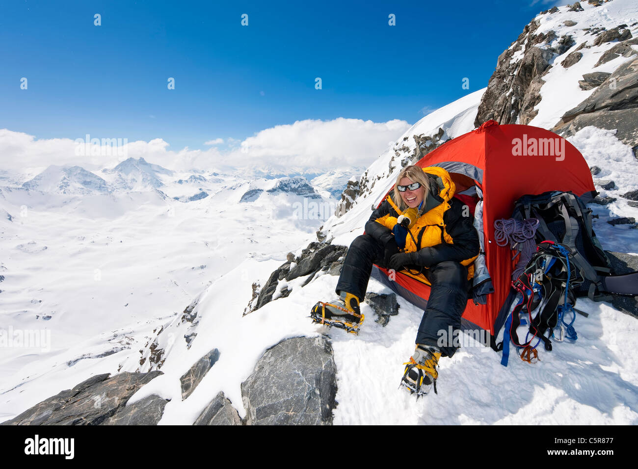 Ein glücklich Bergsteiger sitzen in der Tür von ihrem Zelt Stockfoto