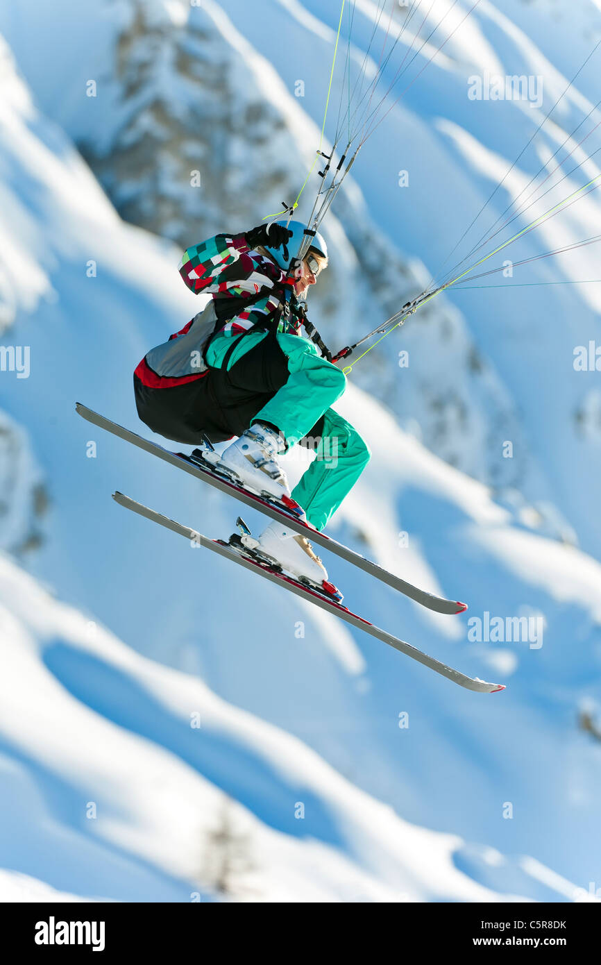 Ein Gleitschirm Pilot ihr Fliegenflügel vorbei an schneebedeckten Bergen. Stockfoto