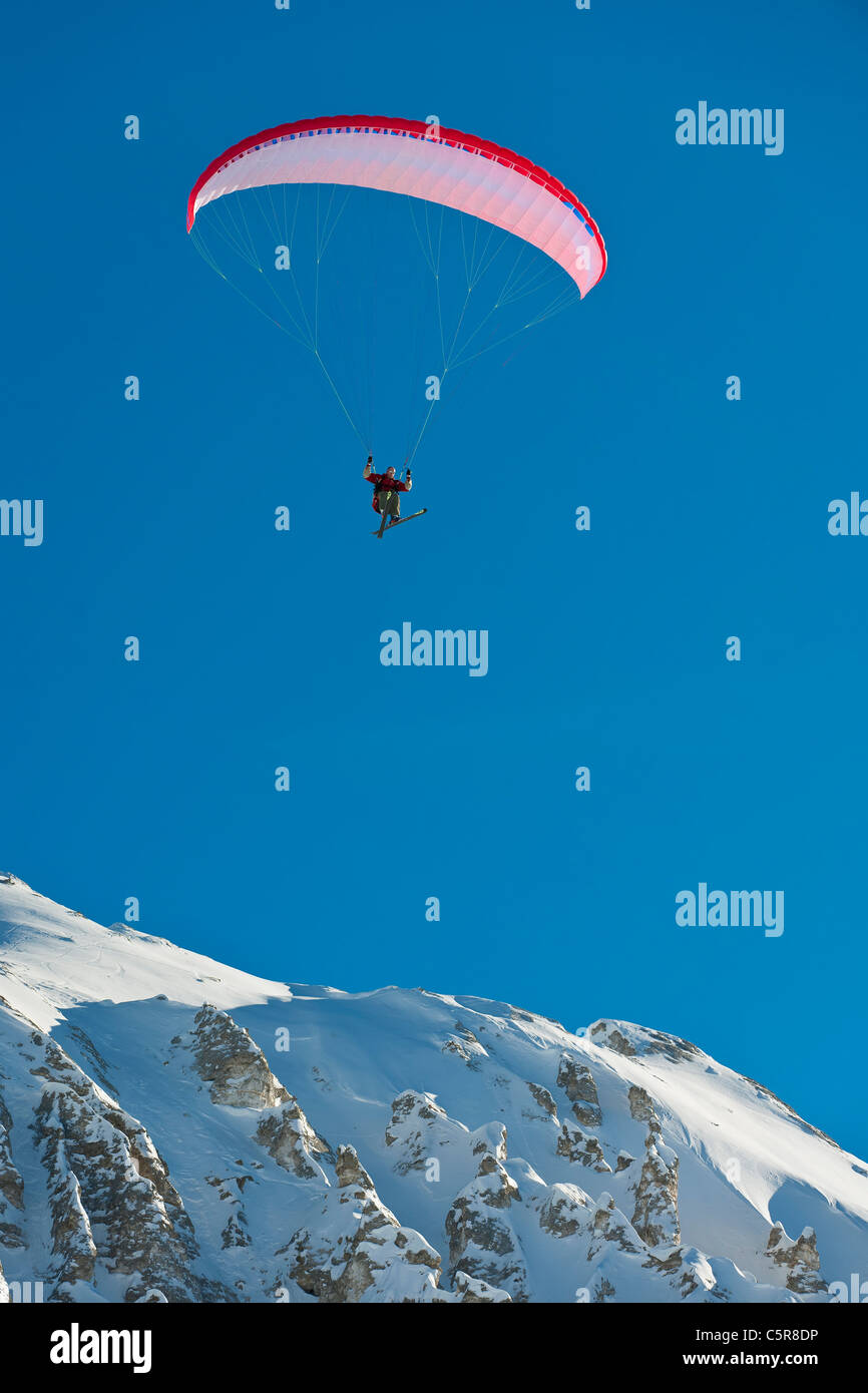 Ein Gleitschirmflieger über schneebedeckte Berge fliegen. Stockfoto