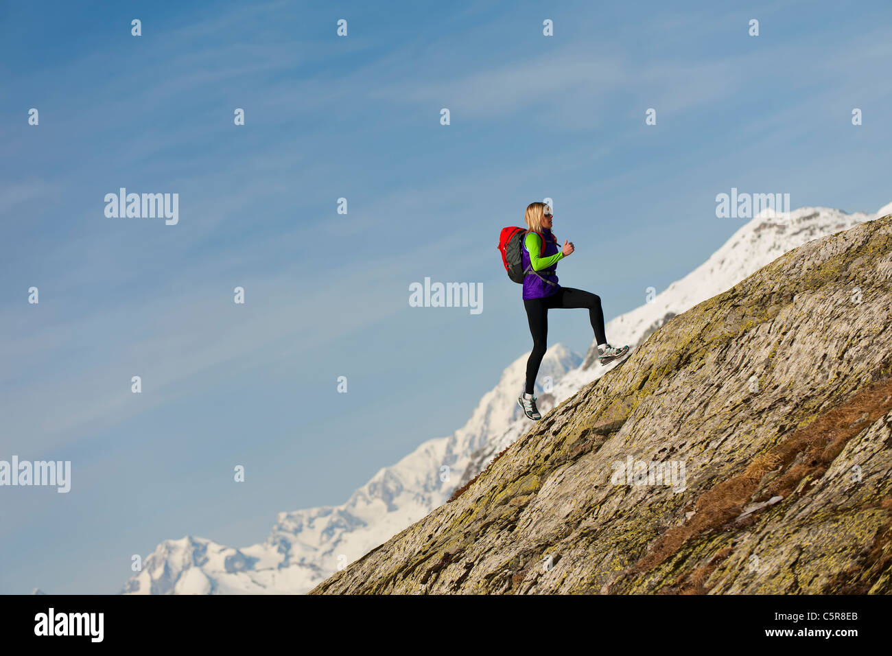 Ein Läufer läuft auf einer steilen Felswand in großer Höhe. Stockfoto