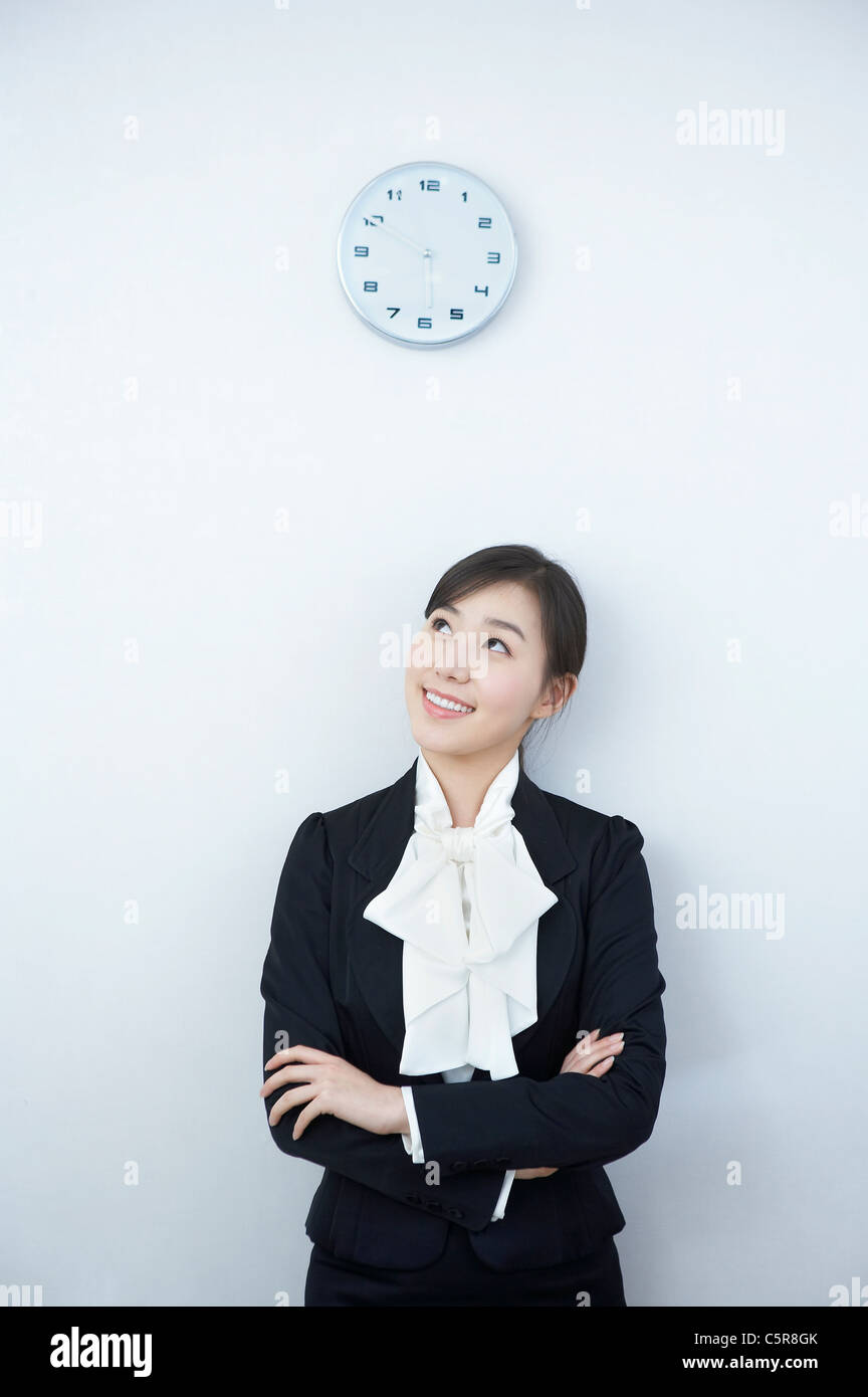 Eine Geschäftsfrau auf der Suche auf die Uhr an der Wand Stockfoto