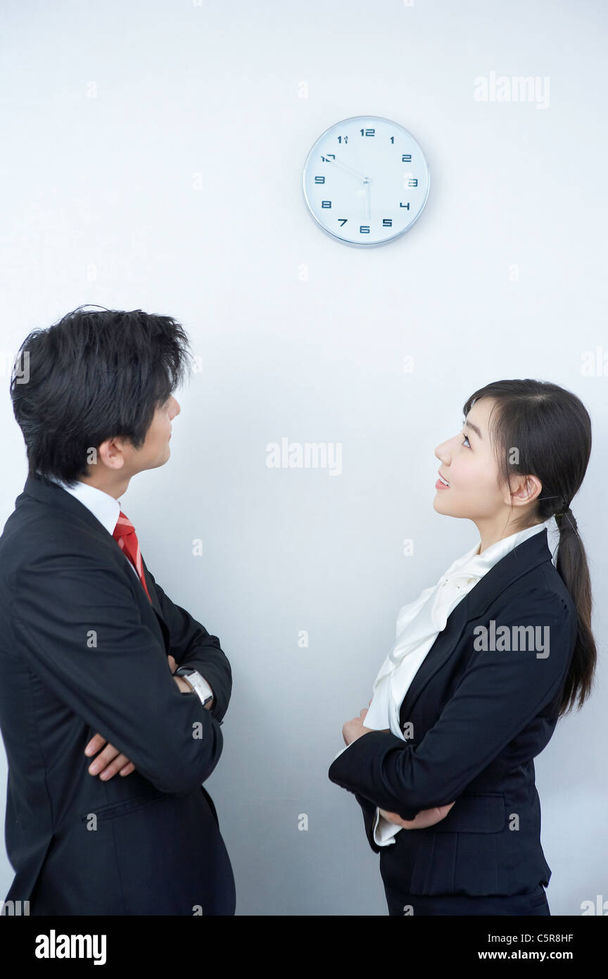 Ein Mann und eine Frau auf der Suche auf die Uhr an der Wand Stockfoto