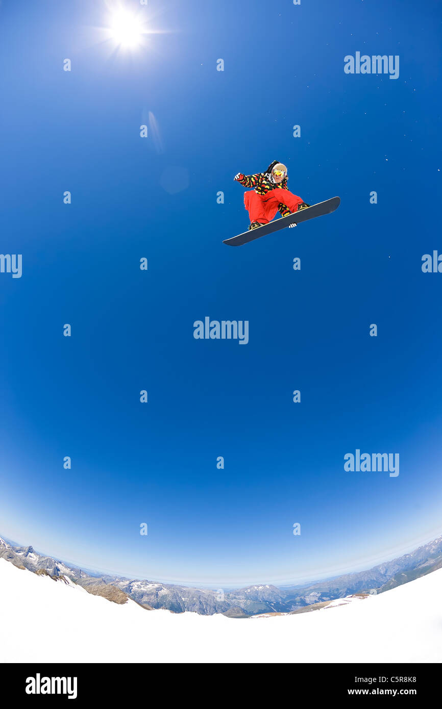 Ein Snowboarder, fliegen hoch über die Berge und Gletscher in der Sonne. Stockfoto