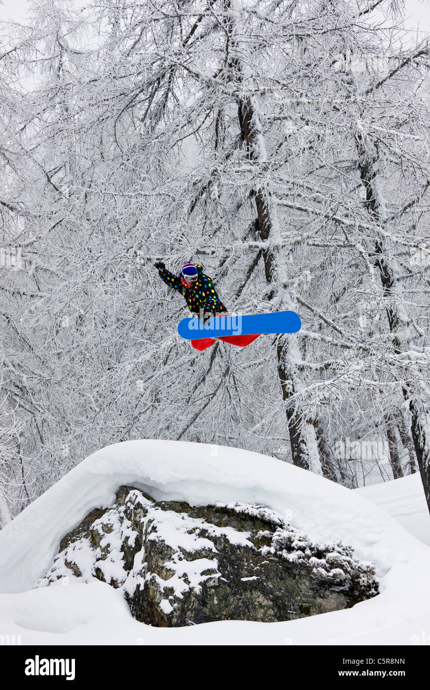Ein Snowboarder in einem verschneiten Wald hoch springen. Stockfoto