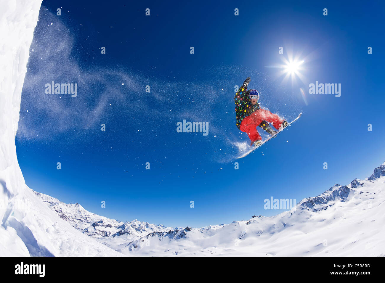 Ein Snowboarder fliegt über Schnee bedeckt Gipfeln. Stockfoto