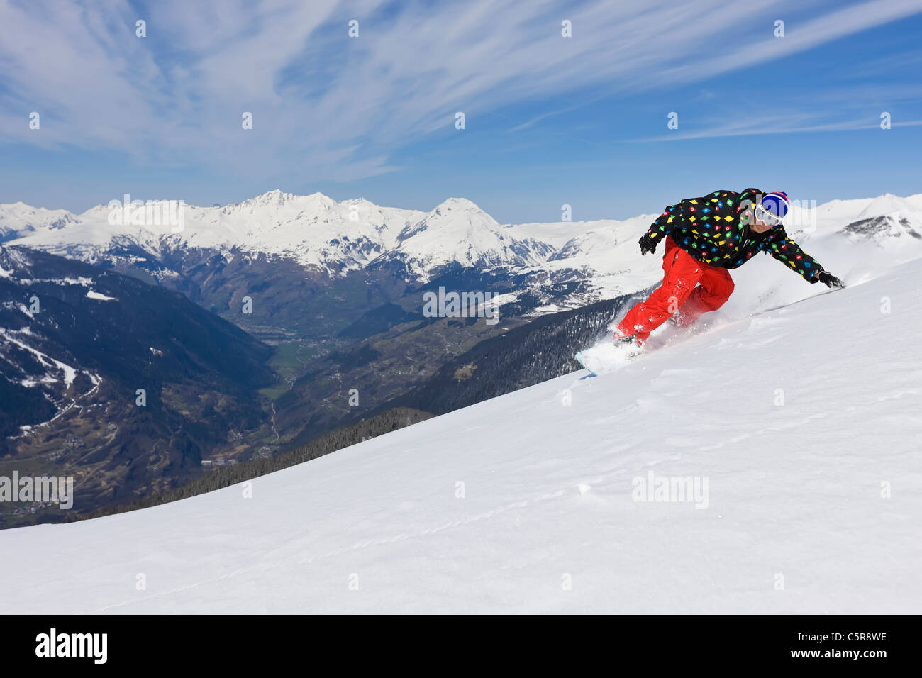 Ein Snowboarder schnitzt durch frischen Pulverschnee mit den Bergtal. Stockfoto