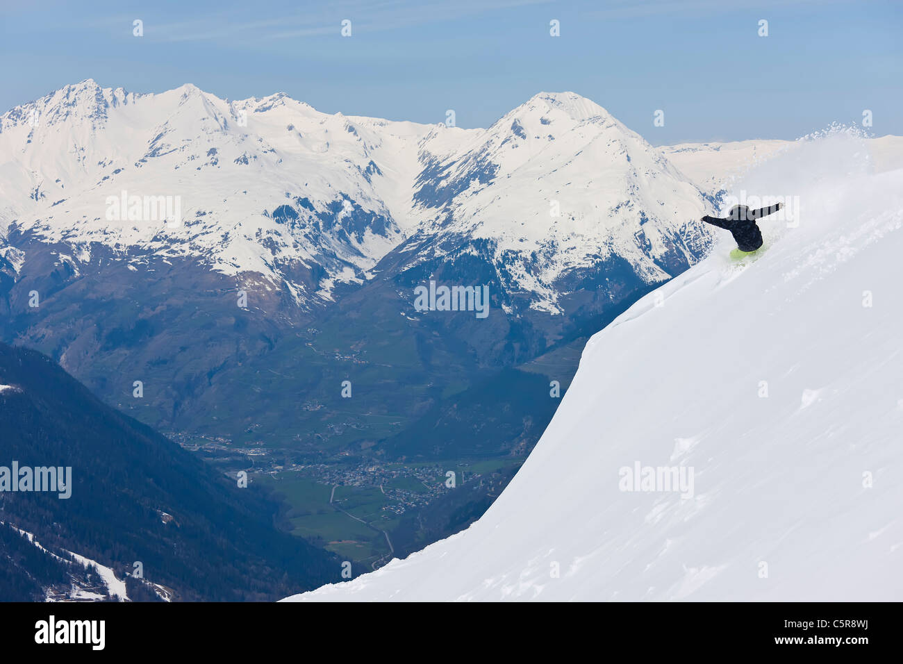 Ein Snowboarder macht eine Pulver auf frischem Pulverschnee hoch über ein grünes Tal zu drehen. Stockfoto