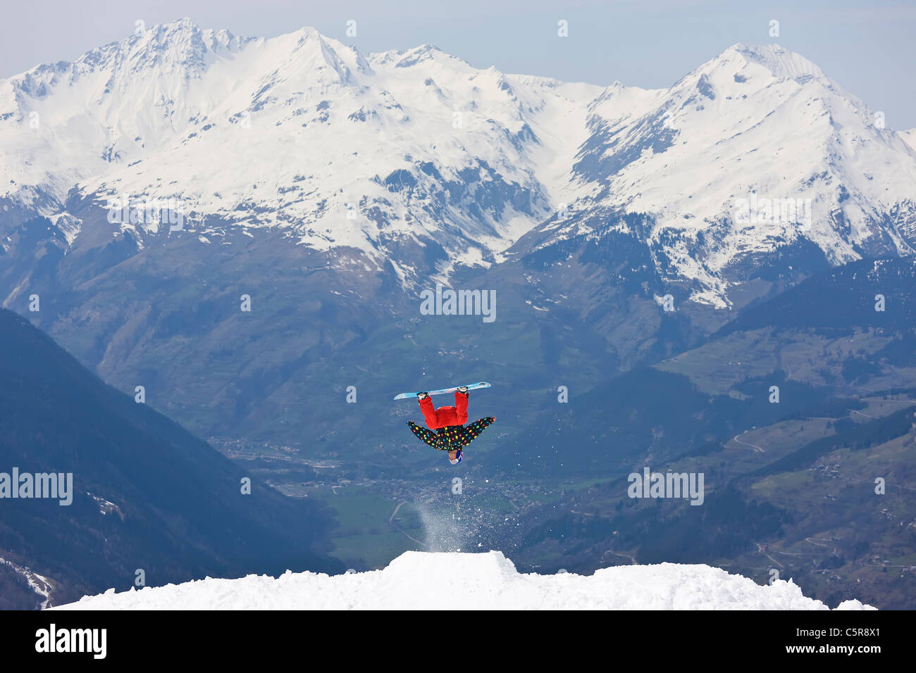 Ein Snowboarder einen große Back Flip einen verschneiten Berg zu tun. Stockfoto