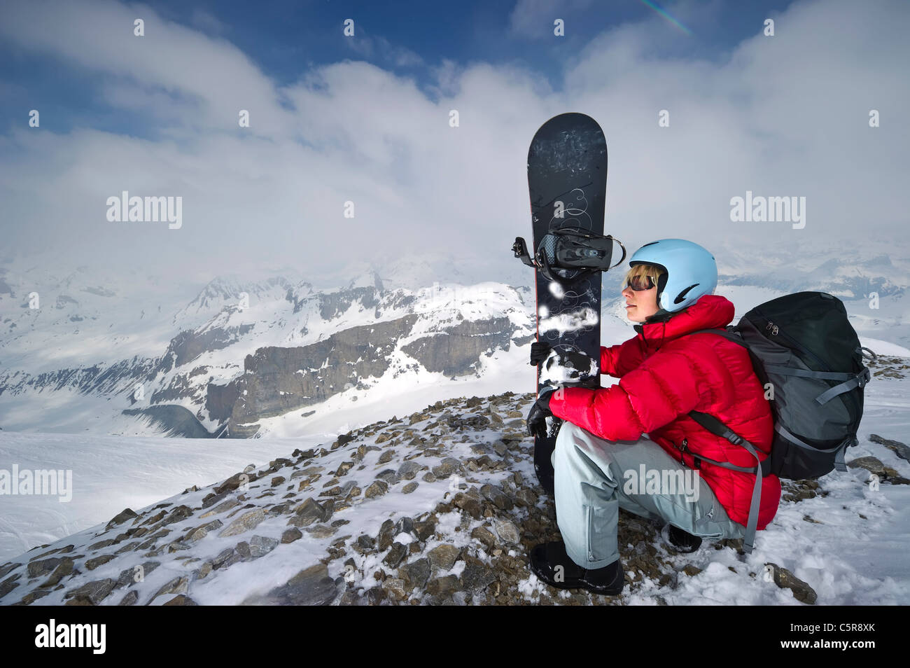 Ein Snowboarder im verschneiten Hochgebirge genießt Blick auf die verschneiten Berge. Stockfoto