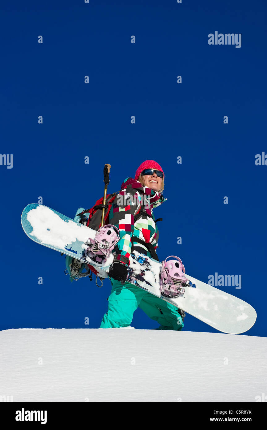 Ein Snowboarder einen Blick auf die verschneiten Berge und lächelt. Stockfoto