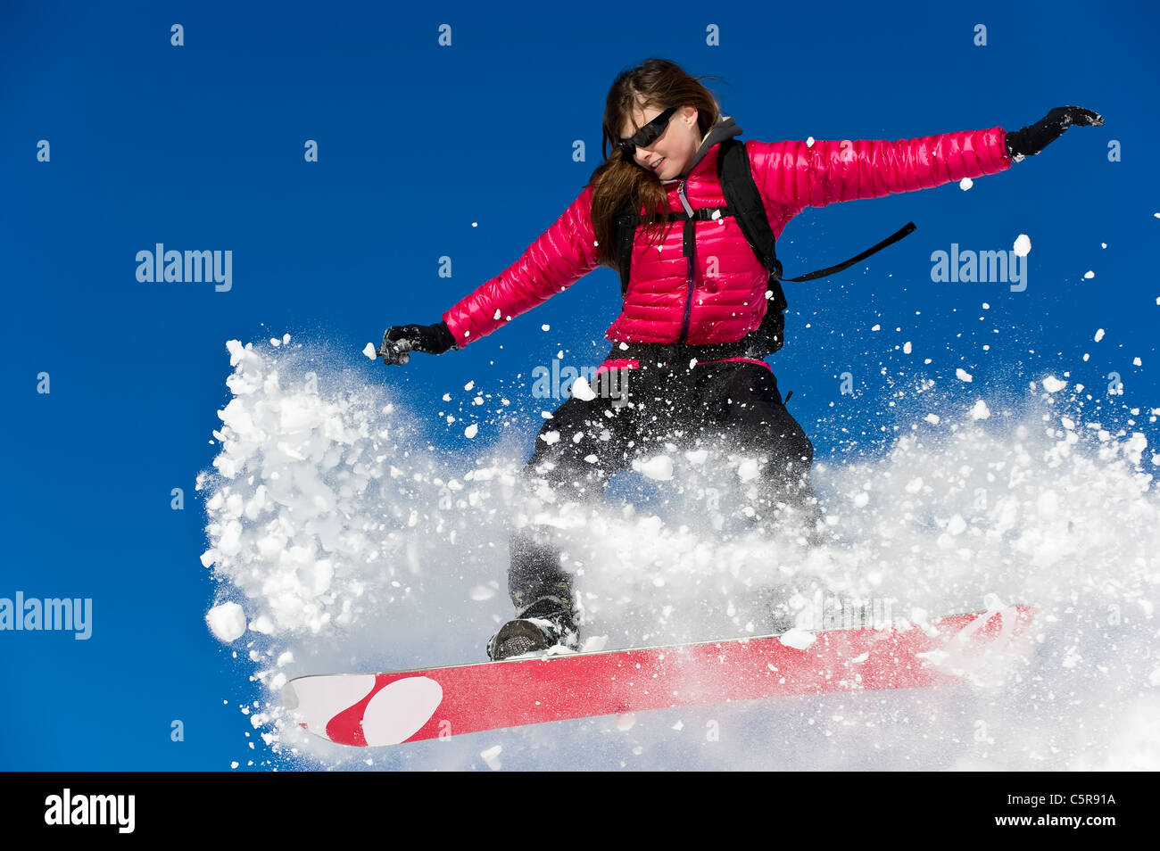 Eine Frau, die Snowboarden springt durch frischen Pulverschnee. Stockfoto