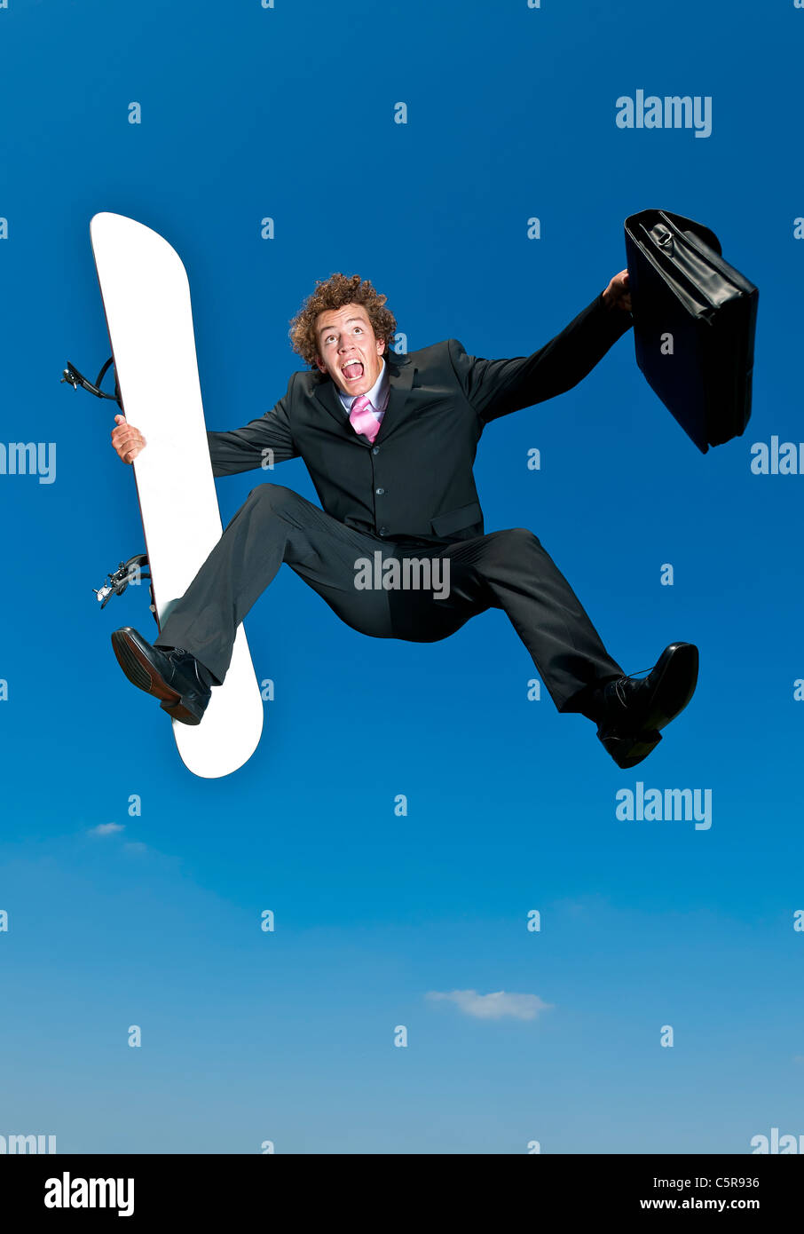 Ein Geschäftsmann freut sich auf seinem Snowboard Urlaub wegzukommen. Stockfoto