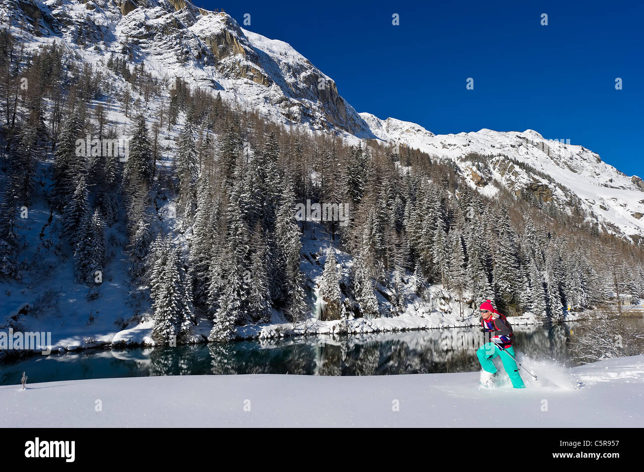 Eine Frau läuft durch Tiefschnee auf Schnee Schuhe Vergangenheit herrlichen schneebedeckten Berge und See. Stockfoto